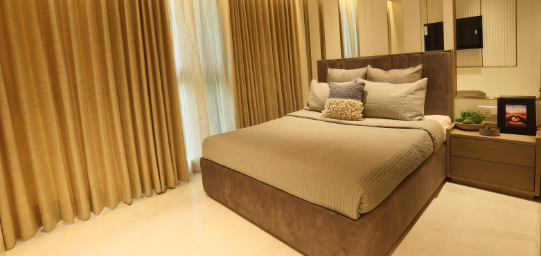 Spacious bedroom of a Runwal Lands 2 bhk apartment in Thane with warm lighting, neat wardrobes and a woman talking on phone.